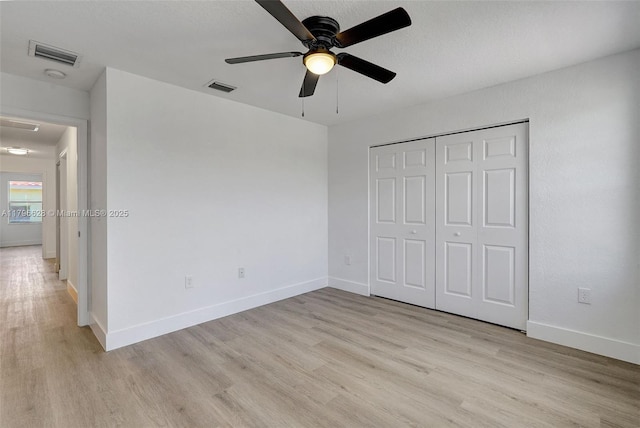 unfurnished bedroom featuring baseboards, light wood-type flooring, visible vents, and a closet