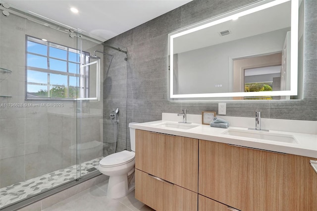 bathroom with a shower stall, tile walls, toilet, and a sink