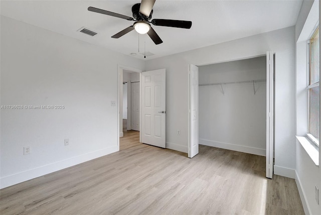 unfurnished bedroom featuring a closet, visible vents, wood finished floors, and baseboards