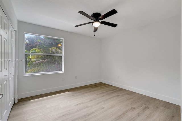 unfurnished bedroom featuring a closet, light wood-style floors, baseboards, and a ceiling fan