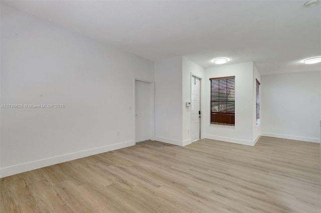 spare room featuring light wood-style floors and baseboards