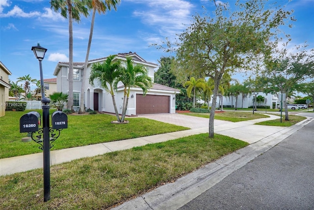 mediterranean / spanish-style home featuring driveway, stucco siding, a front lawn, and a garage