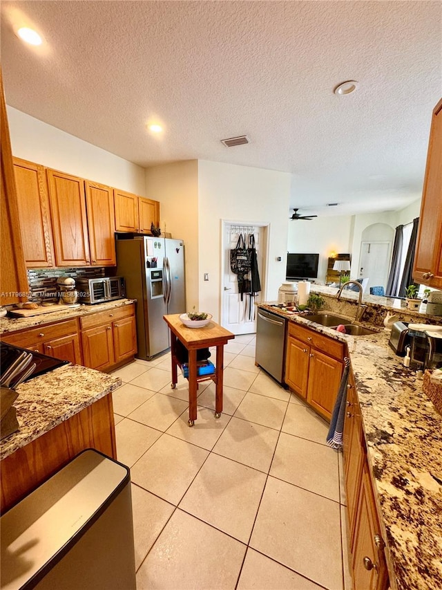 16724 NW 8th St, Pembroke Pines, FL 33028 - kitchen featuring brown cabinetry, light stone counters, visible vents, a sink, and stainless steel appliances