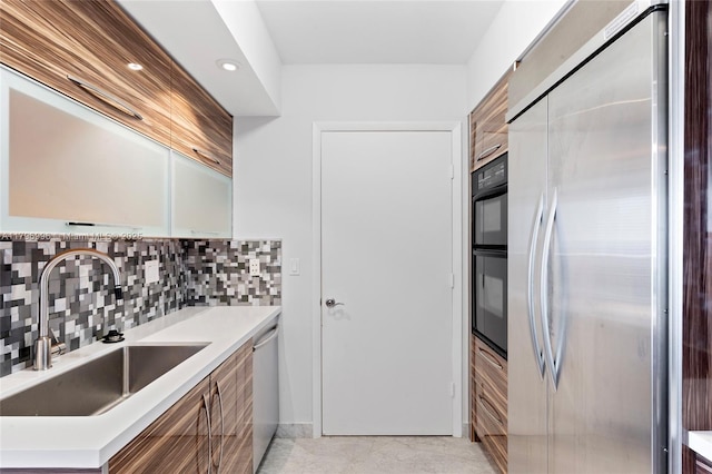 kitchen featuring appliances with stainless steel finishes, a sink, tasteful backsplash, light countertops, and recessed lighting