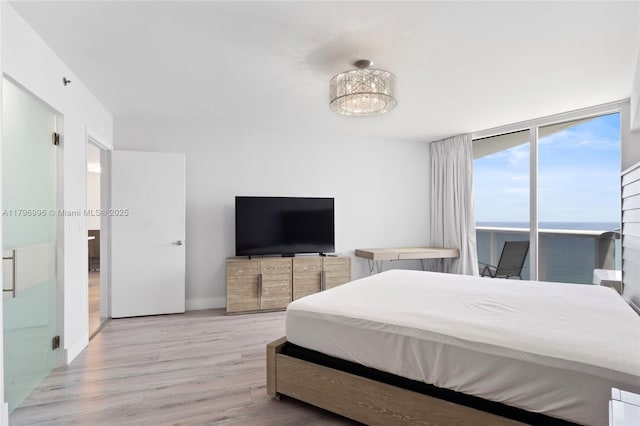 bedroom featuring wood finished floors, expansive windows, a chandelier, and access to exterior
