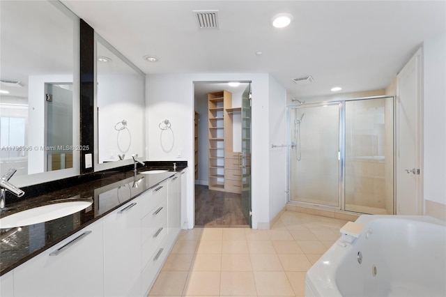 bathroom with a stall shower, a tub with jets, a spacious closet, double vanity, and recessed lighting