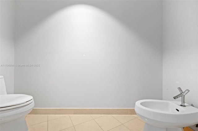 bathroom with toilet, tile patterned flooring, baseboards, and a sink