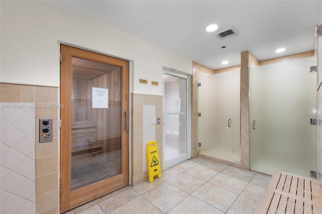 bathroom with tile patterned floors, a sauna, tile walls, and a shower stall