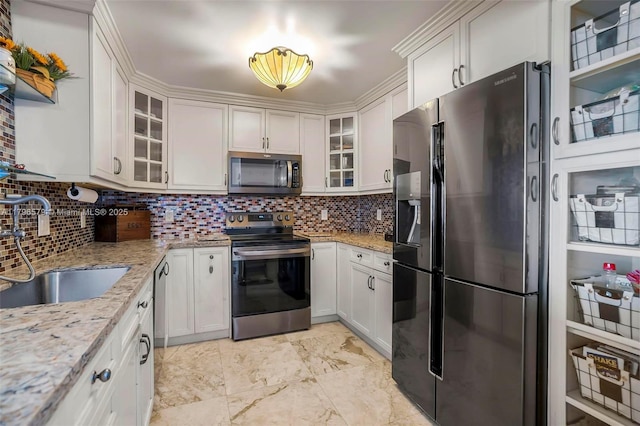 kitchen featuring appliances with stainless steel finishes, a sink, decorative backsplash, and light stone countertops