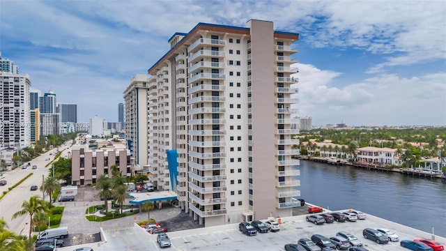 view of property with a water view, a view of city, and uncovered parking