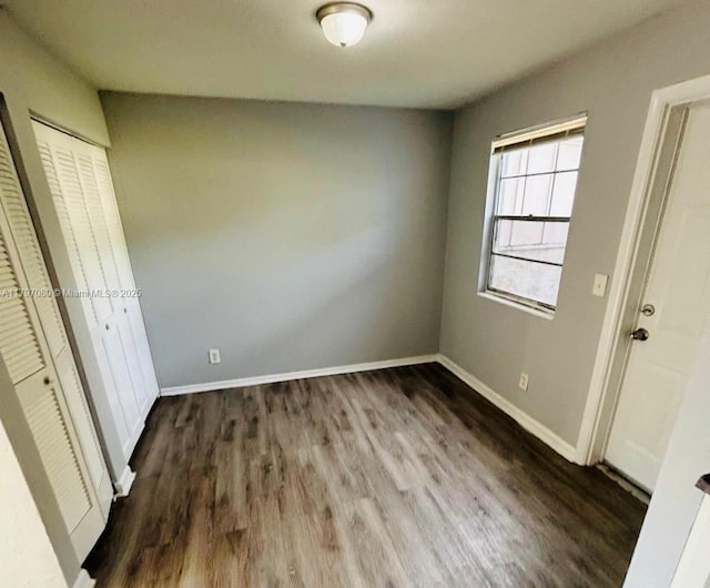 unfurnished bedroom with dark wood-type flooring and baseboards
