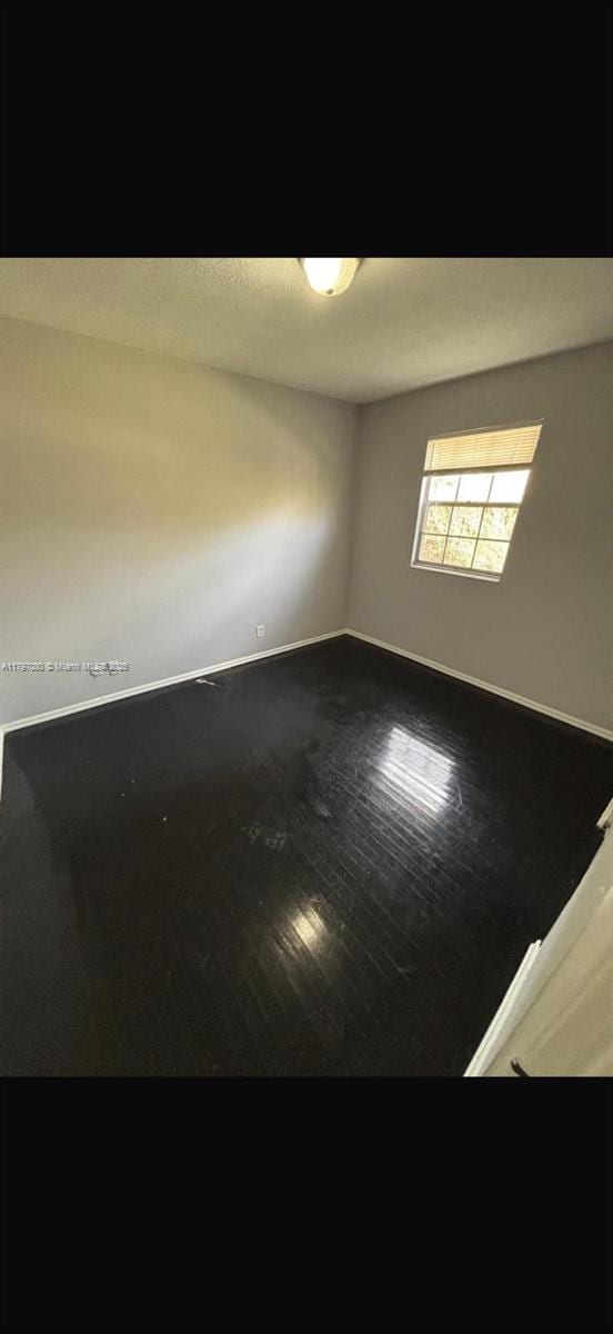 empty room with wood finished floors and baseboards