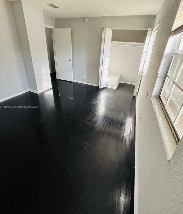 spare room with wood-type flooring, baseboards, and visible vents