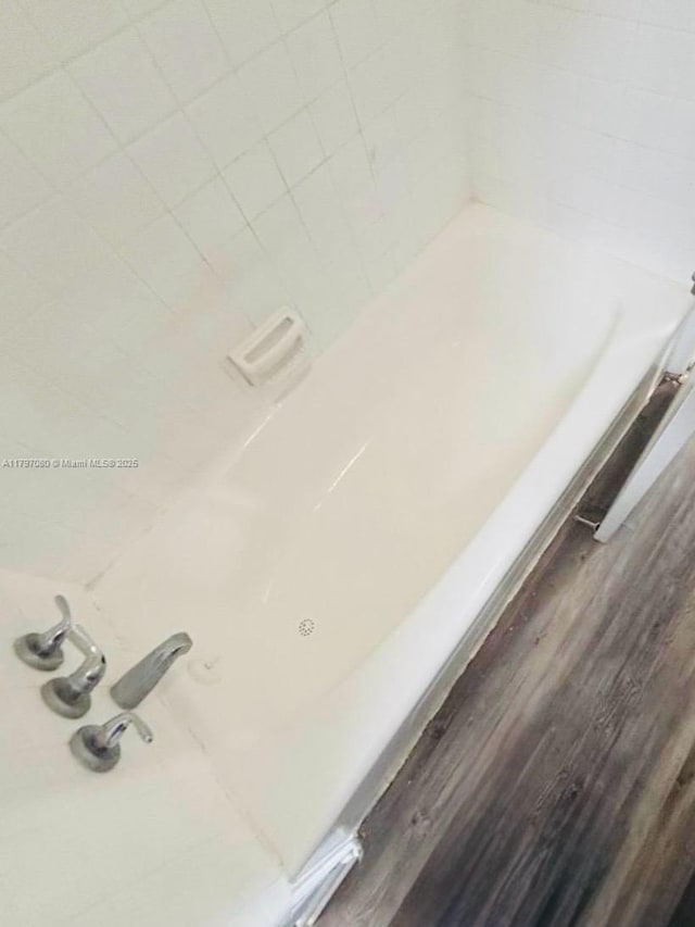 room details featuring a tub to relax in and wood finished floors