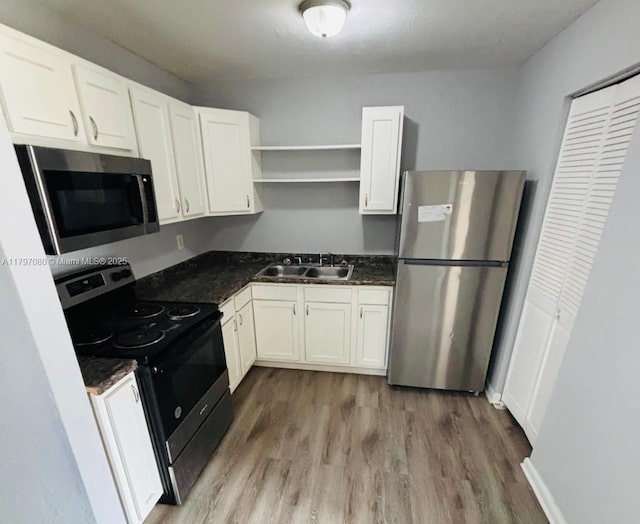 kitchen featuring a sink, stainless steel appliances, wood finished floors, open shelves, and white cabinets