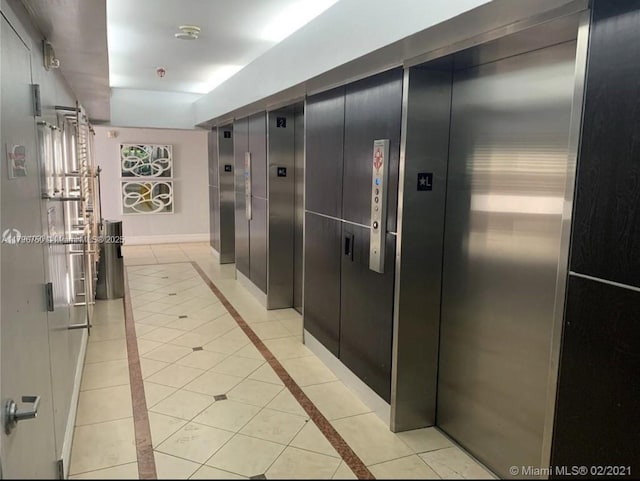 corridor featuring elevator and light tile patterned flooring