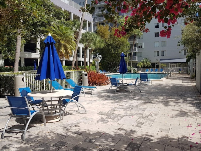 community pool with fence, a patio, and outdoor dining area