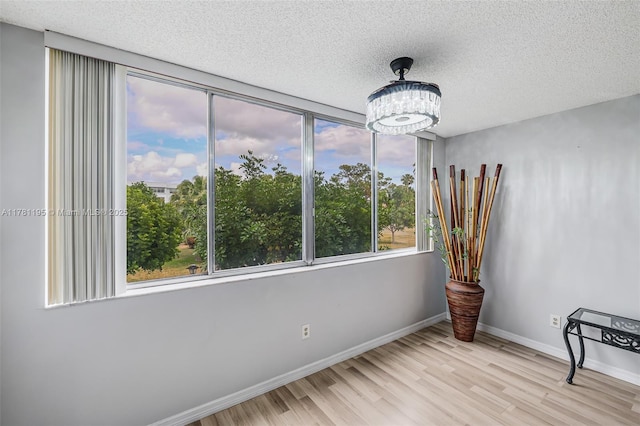 6698 N 10th Ave N Unit 218, Lake Worth, FL 33467 - empty room featuring an inviting chandelier, a textured ceiling, wood finished floors, and baseboards