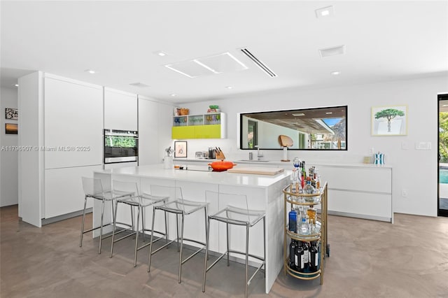 2020 NE 121st Rd, North Miami, FL 33181 - kitchen featuring a breakfast bar area, a sink, white cabinetry, a kitchen island, and oven