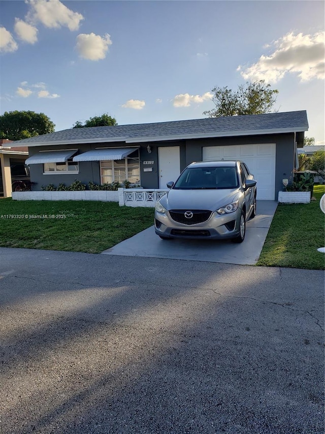 view of front of property featuring stucco siding, a garage, a front lawn, and driveway