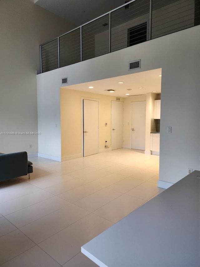 unfurnished room with baseboards, visible vents, and a high ceiling