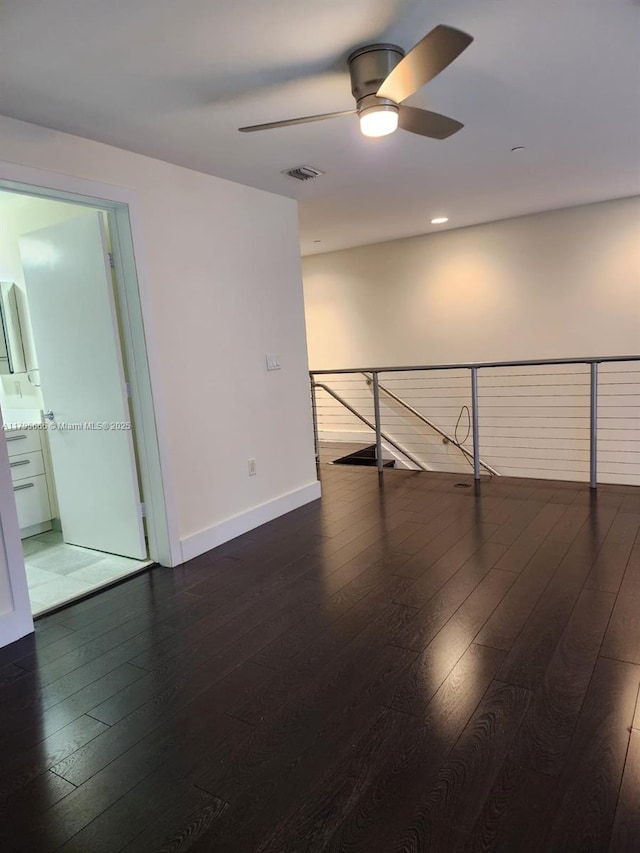 spare room with wood-type flooring, visible vents, baseboards, and ceiling fan