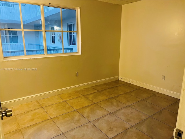 spare room with baseboards and tile patterned flooring