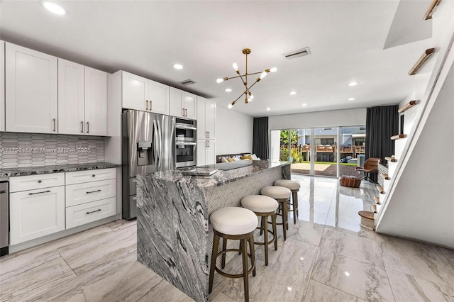 kitchen with stainless steel appliances, tasteful backsplash, marble finish floor, dark stone counters, and visible vents