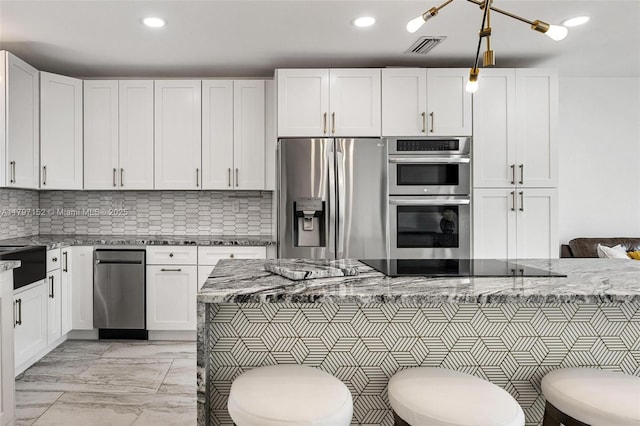 kitchen with backsplash, appliances with stainless steel finishes, light stone counters, and white cabinetry