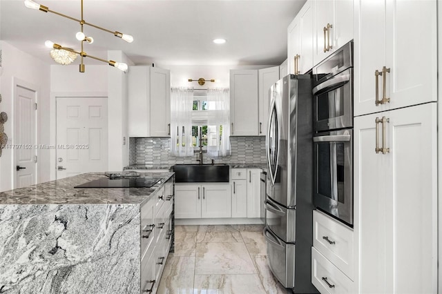 kitchen featuring marble finish floor, a sink, white cabinetry, backsplash, and appliances with stainless steel finishes