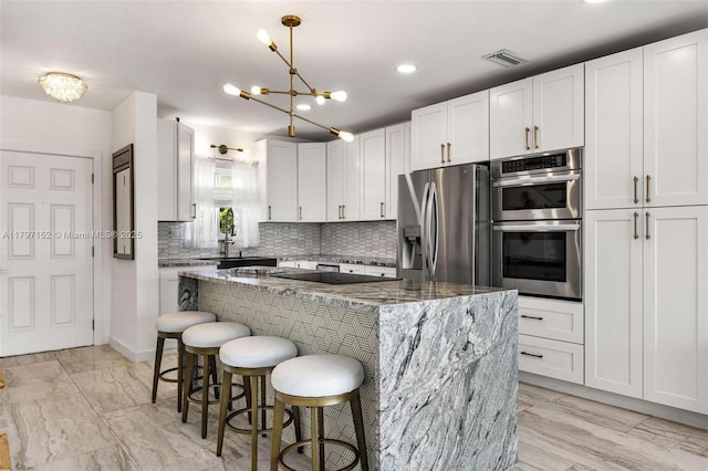 kitchen with stainless steel appliances, a breakfast bar area, visible vents, a center island, and stone counters
