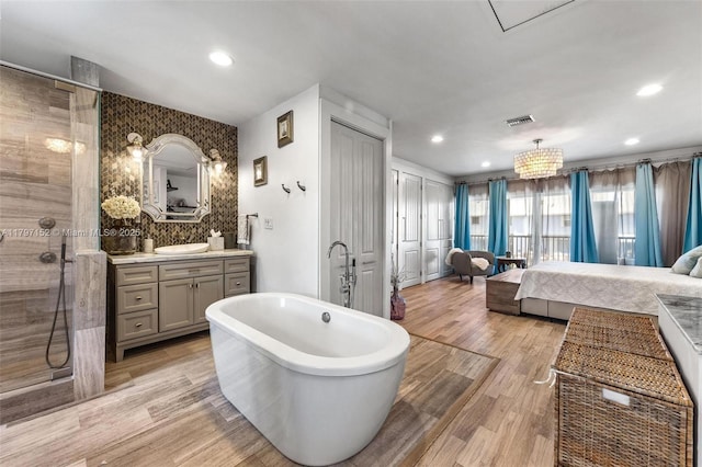 bathroom with visible vents, tiled shower, connected bathroom, a soaking tub, and wood finished floors