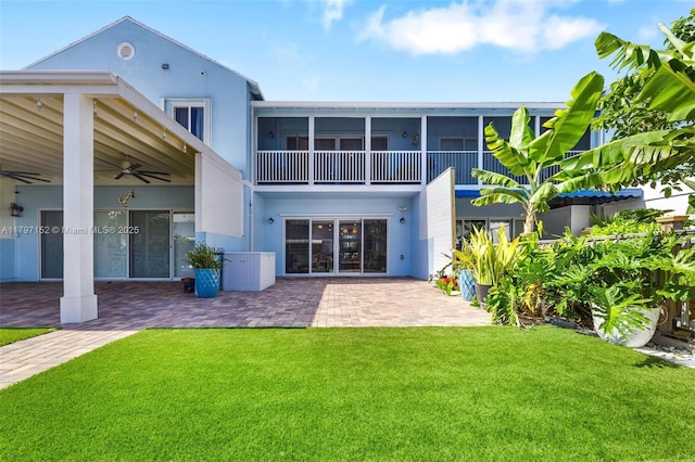 back of property featuring a yard, stucco siding, a ceiling fan, and a patio area