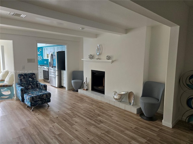 living room with baseboards, a fireplace, visible vents, and wood finished floors