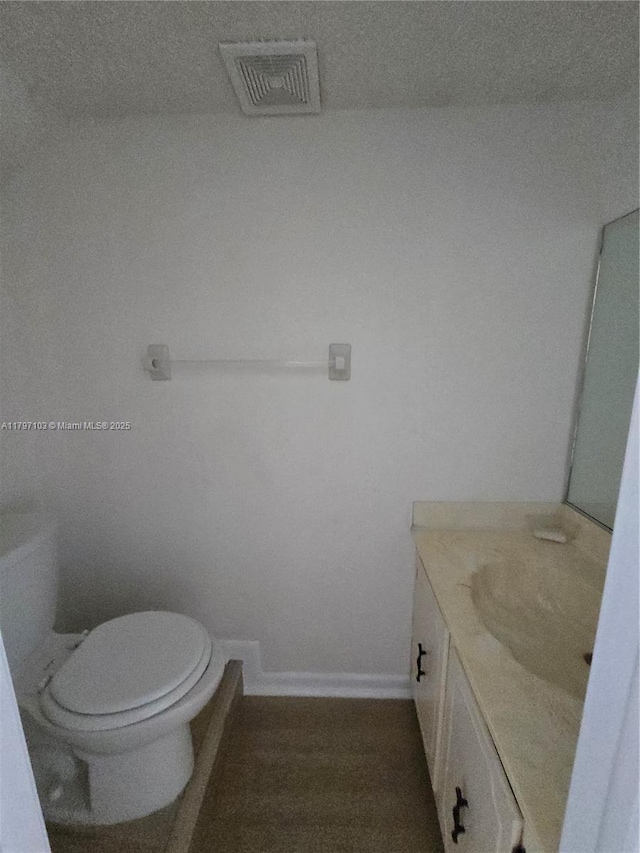 bathroom featuring toilet, baseboards, vanity, and visible vents