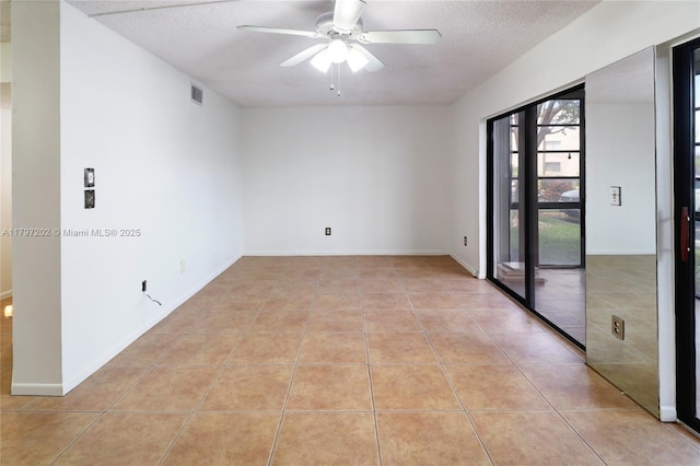 unfurnished room with a ceiling fan, visible vents, light tile patterned flooring, and a textured ceiling