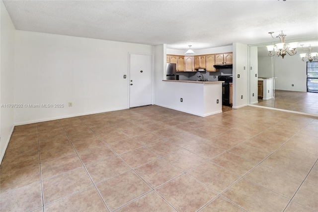 kitchen featuring freestanding refrigerator, light tile patterned flooring, open floor plan, a peninsula, and a chandelier