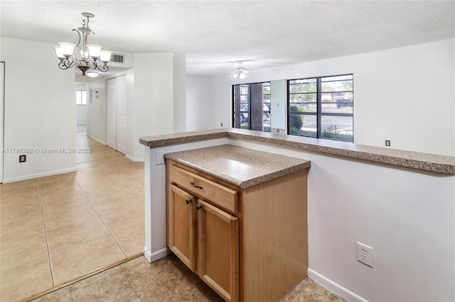 kitchen with ceiling fan with notable chandelier, light tile patterned flooring, visible vents, pendant lighting, and baseboards