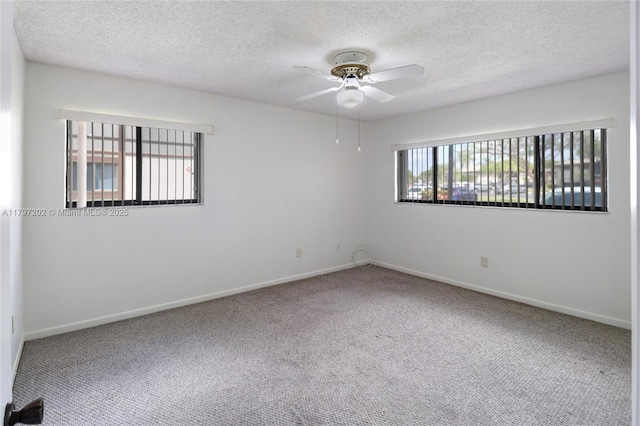 carpeted spare room featuring a textured ceiling, baseboards, and ceiling fan