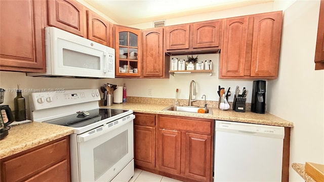 kitchen with glass insert cabinets, white appliances, a sink, brown cabinets, and light countertops
