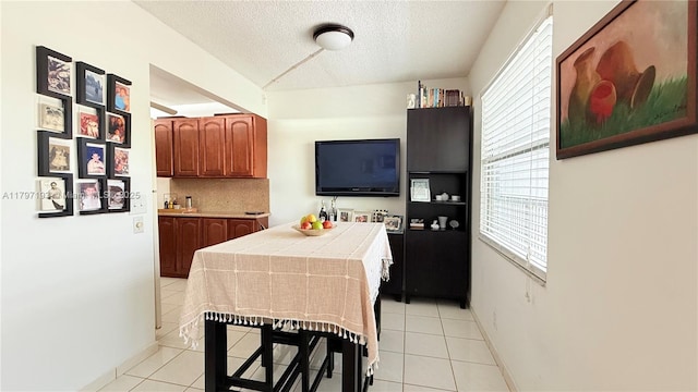 kitchen featuring light tile patterned floors, brown cabinets, a textured ceiling, tile countertops, and decorative backsplash