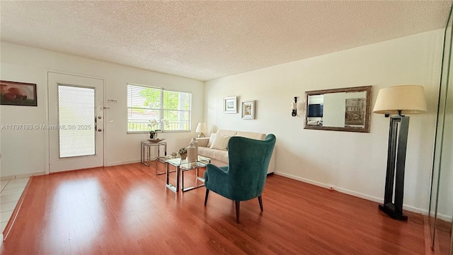 sitting room with a textured ceiling, baseboards, and wood finished floors