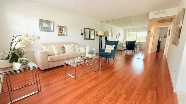 13450 SW 3rd St Unit 308D, Pembroke Pines, FL 33027 - living room with light wood finished floors, a textured ceiling, visible vents, and baseboards