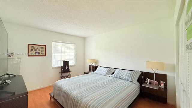 13450 SW 3rd St Unit 308D, Pembroke Pines, FL 33027 - bedroom with a textured ceiling, baseboards, and wood finished floors