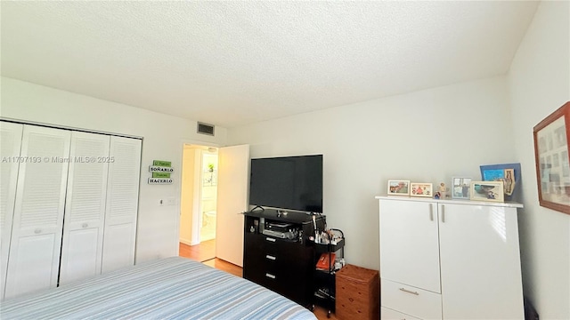 bedroom with a closet, a textured ceiling, and visible vents