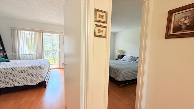 bedroom with a textured ceiling, wood finished floors, and access to exterior
