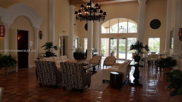tiled living area with a wealth of natural light, ornate columns, and a towering ceiling