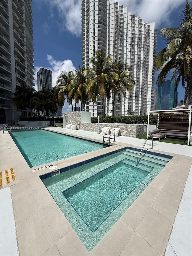 community pool featuring a city view, a patio, and a community hot tub