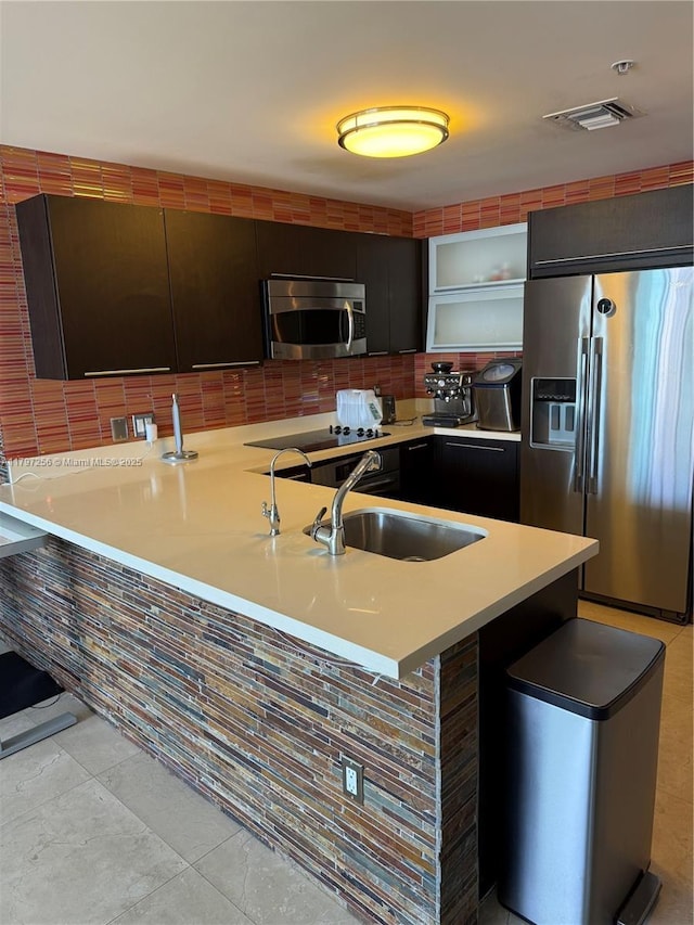 kitchen with appliances with stainless steel finishes, a sink, light countertops, tasteful backsplash, and modern cabinets
