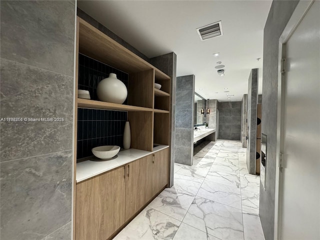 full bathroom with marble look tiles, a garden tub, and tile walls